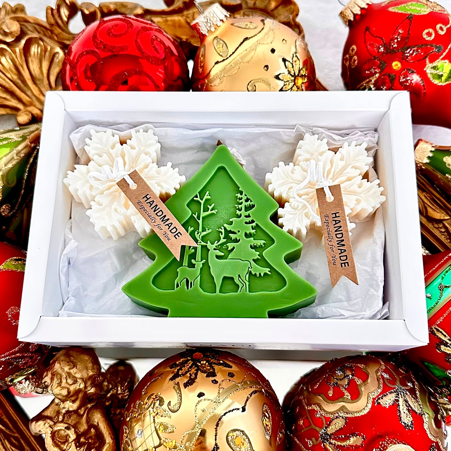Green Christmas tree candle with two white snowflake candles in a white gift box.