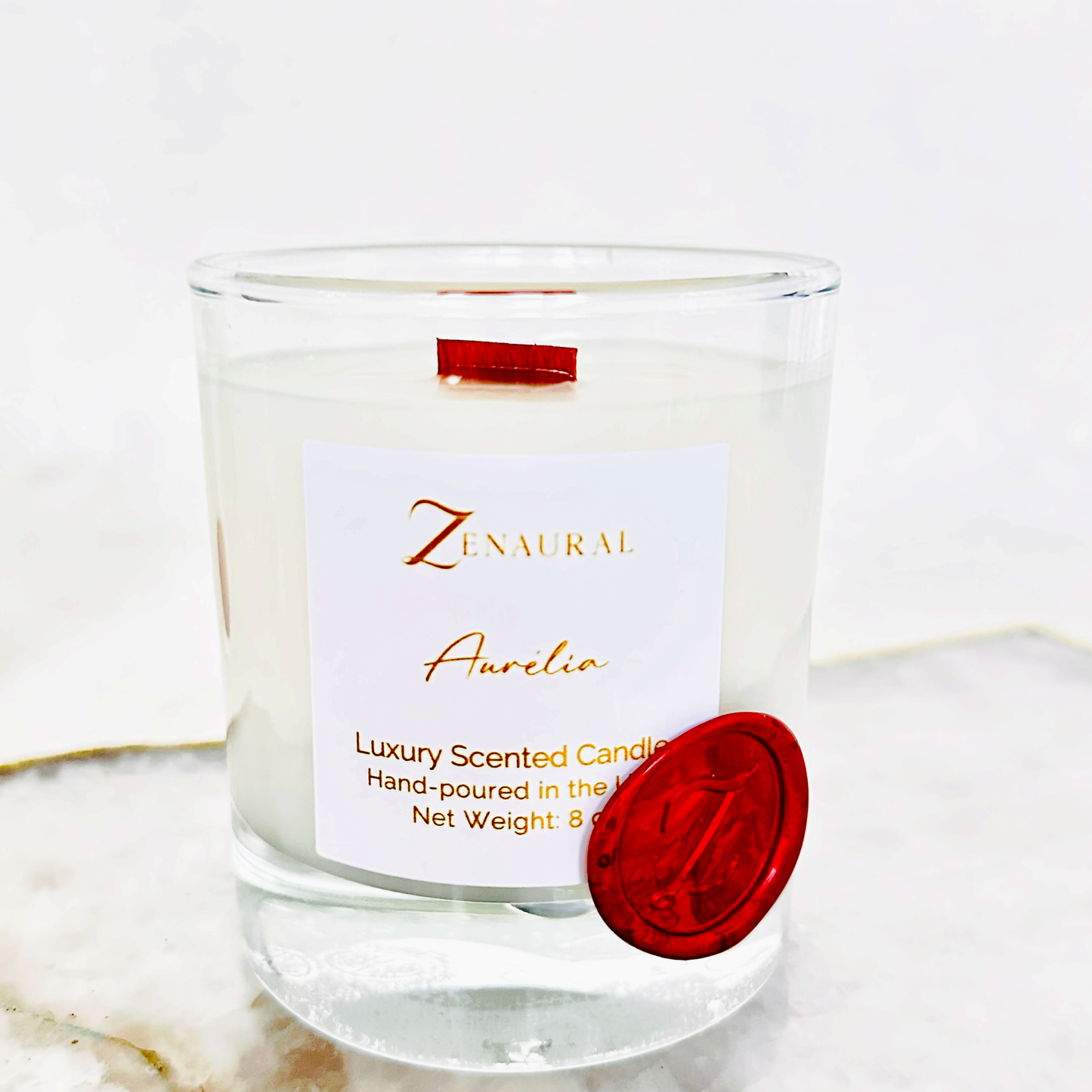 Aurelia — warm gold glass candle with white Zenaural label and wooden wick, Veloria Collection by Zenaura Studio.